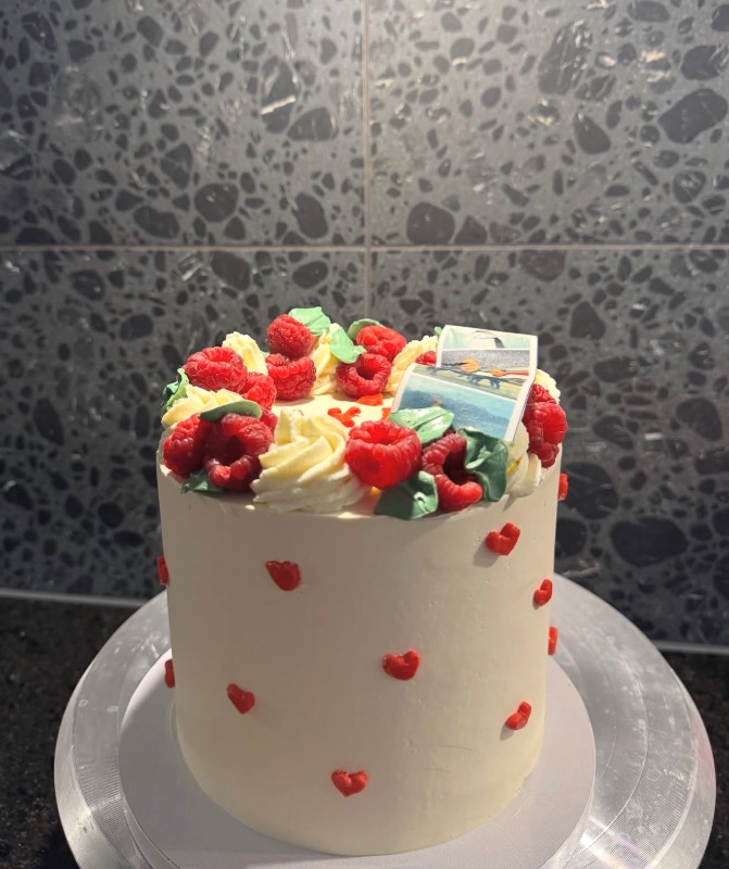 Gâteau blanc aux framboises décoré de petits cœurs rouges